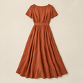 Vestido midi terracota sobre fondo beige de estudio