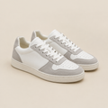 Tenis casuales blancos y grises sobre fondo beige de estudio